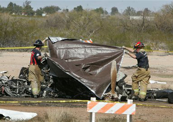 Casa Grande Firefighters cover the bodies of two victims of a plane crash Wednesday Feb. 6, 2013 at Casa Grande Municipal Airport in Casa Grande, Ariz. Federal Aviation Administration officials say the twin-engine turbo prop went down at 11:35 a.m. Wednesday as it was landing and the craft was destroyed by fire. FAA spokesman Ian Gregor says the cause of the crash is unclear. He says an FAA investigator is en route to the scene. Casa Grande police and fire officials didn't immediately release the names of the two killed.