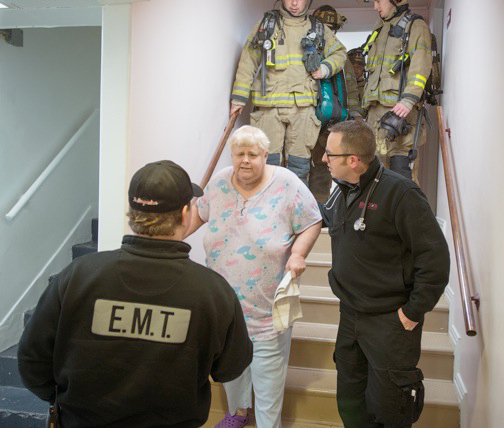 Fire and EMS crews assist residents from the building.