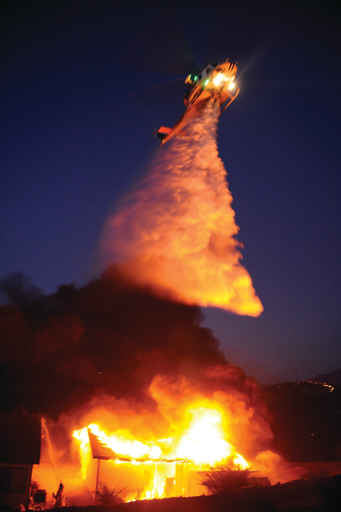 Aug. 11: Riverside County, CA &ndash; The 'Silver Fire,' which started in Riverside County, CA, on Aug. 7, 2013, spread across the San Jacinto Mountains burning 20,292 acres. Twelve people were injured including 11 firefighters. As of Aug. 11, the fire was 95% contained. During the height of the fire, more than 1,400 firefighters using 62 engines, 59 fire crews, nine helicopters, five dozers and 10 water tenders battled the blaze. Several photographers, including Shawn Kaye (shown in bottom left of photo), grabbed a garden hose and stopped fire in a garage from extending into a house. As Kaye was operating, Mike Meadows found some fire crews to respond.