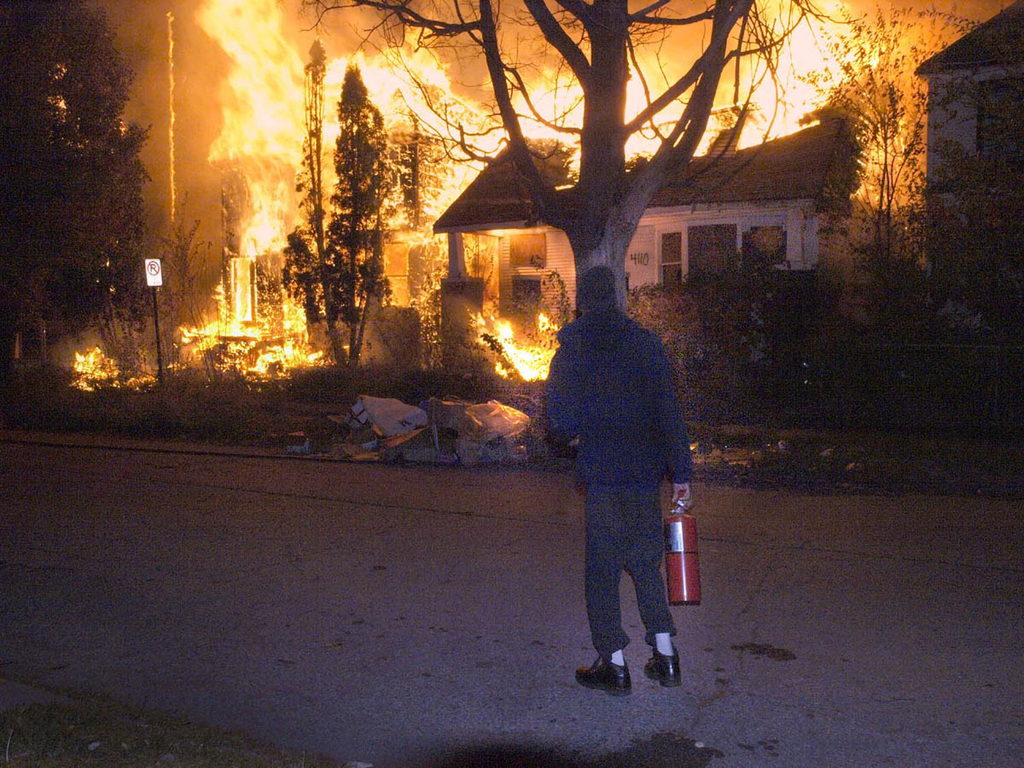 A frustrated resident waiting for companies to arrive, watches as three vacant houses burn on the East Side.