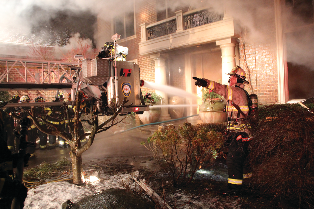 Deputy Chief Mark Kiess gives instructions as Tower Ladder 8724 operates its master stream through the front door.