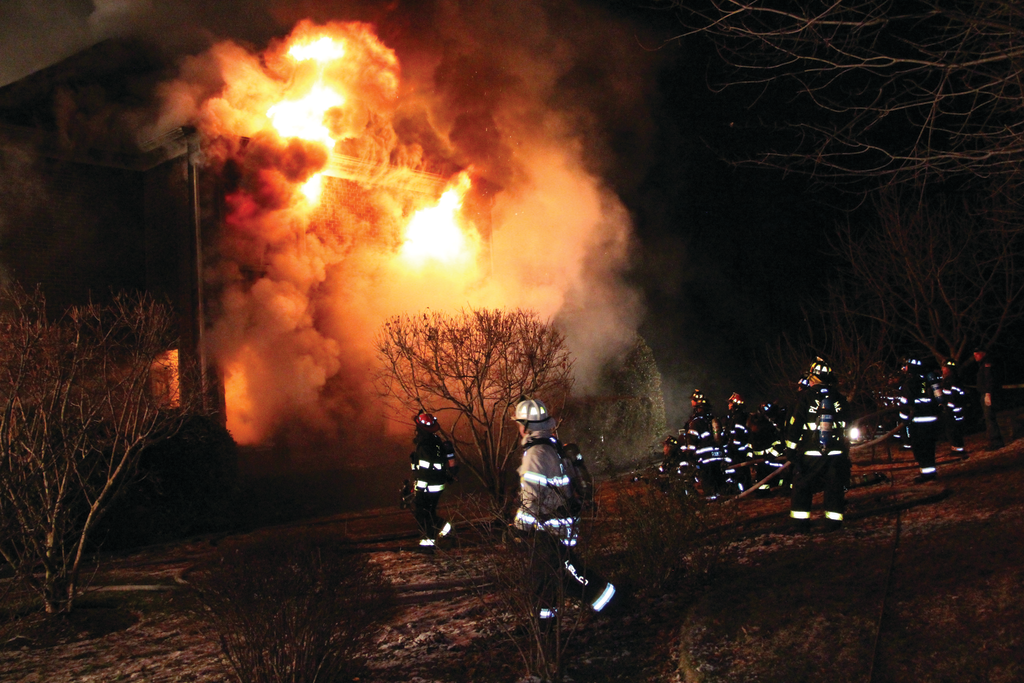 A view from side 4 (Delta) shows the fire exposing from the second level as members prepare to operate a 2-1/2-inch hoseline.