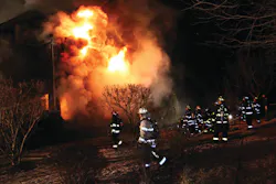 A view from side 4 (Delta) shows the fire exposing from the second level as members prepare to operate a 2-1/2-inch hoseline. A view from side 4 (Delta) shows the fire exposing from the second level as members prepare to operate a 2-1/2-inch hoseline.