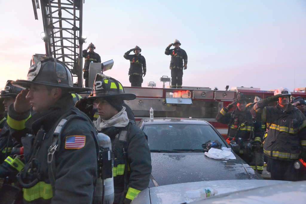 Firefighters salute as the body of Boston Fire Department Lieutenant Edward J. Walsh is removed from the structure in which he and Firefighter Michael R. Kennedy were killed on March 26, 2014. See page 48.