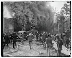 This undated photo shows a Hearst Metrotone News crew filming a silent newsreel featuring a building fire. The company was renamed News of the Day in 1916. It is interesting to note the wooden platform being used by one cameraman. It is not clear whether the fire was staged. This undated photo shows a Hearst Metrotone News crew filming a silent newsreel featuring a building fire. The company was renamed News of the Day in 1916. It is interesting to note the wooden platform being used by one cameraman. It is not clear whether the fire was staged.