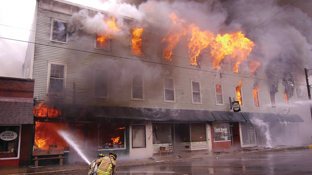 The time of the first page was 1:15 P.M. Ten minutes into the incident, only the Buckeye Block building&rsquo;s second floor (Buckeye Hall auditorium) and third floor 3 (storage space) are well-involved. This view is of side C looking east toward side D.