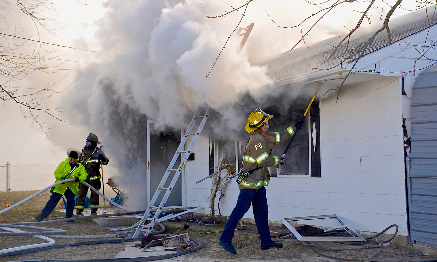 Firefighters work to open up the burning single-family house.