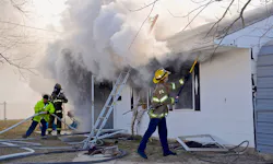 Firefighters work to open up the burning single-family house. Firefighters work to open up the burning single-family house.