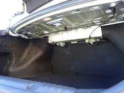 The two black trunk torsion rods of this KIA sedan are visible beneath the rear speaker deck. Note the mild steel mounting bracket for the torsion rods at the left of this image. This is where they can be pried free of the mount and removed. The two black trunk torsion rods of this KIA sedan are visible beneath the rear speaker deck. Note the mild steel mounting bracket for the torsion rods at the left of this image. This is where they can be pried free of the mount and removed.