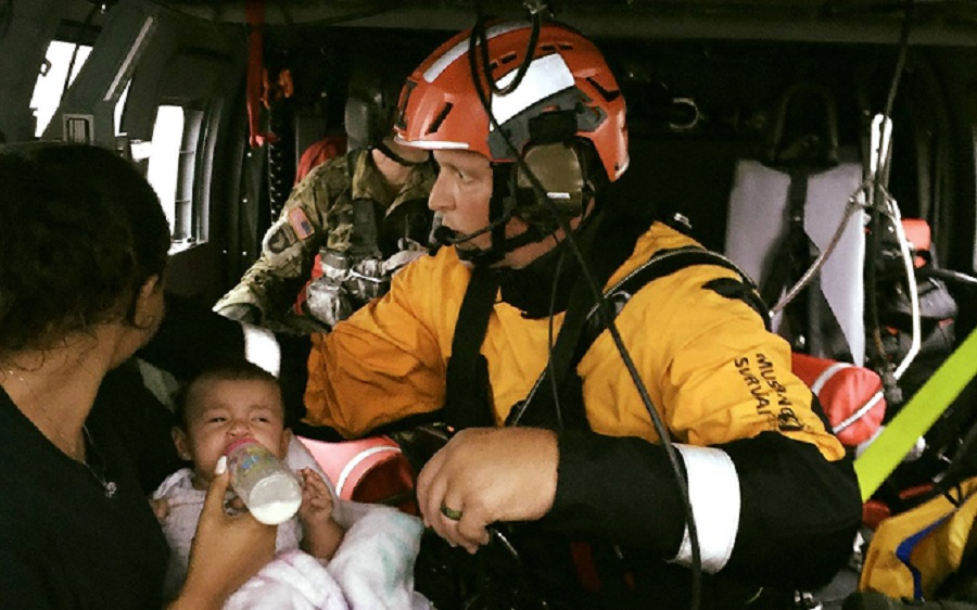 Texas Task Force 1 rescuer Matt Geller, a veteran Dallas firefighter, attends to a woman and her child aboard a helicopter during Hurricane Harvey rescue efforts.