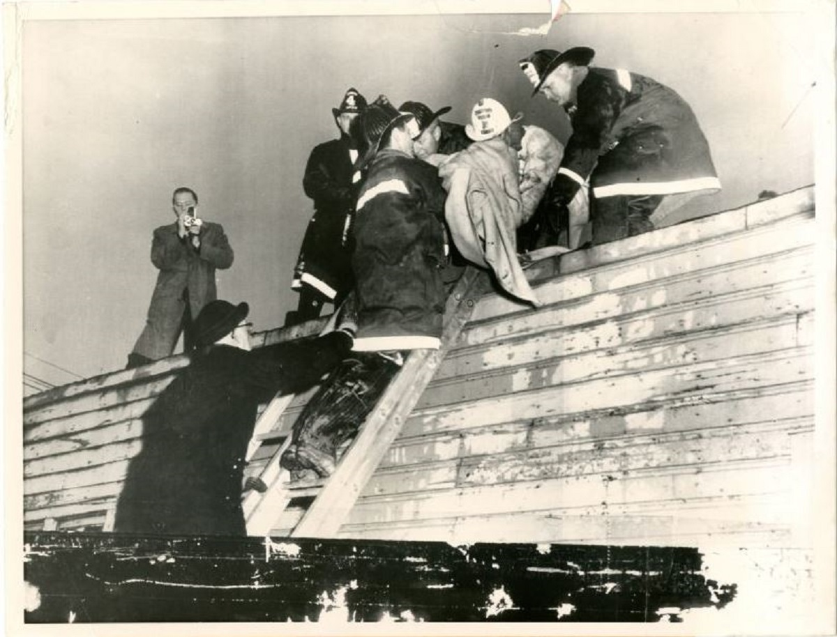 A vintage photo showing one of 18 victims being removed from the scene of the Moonglow Hotel fire in Niagara Falls, NY, in November 1957.