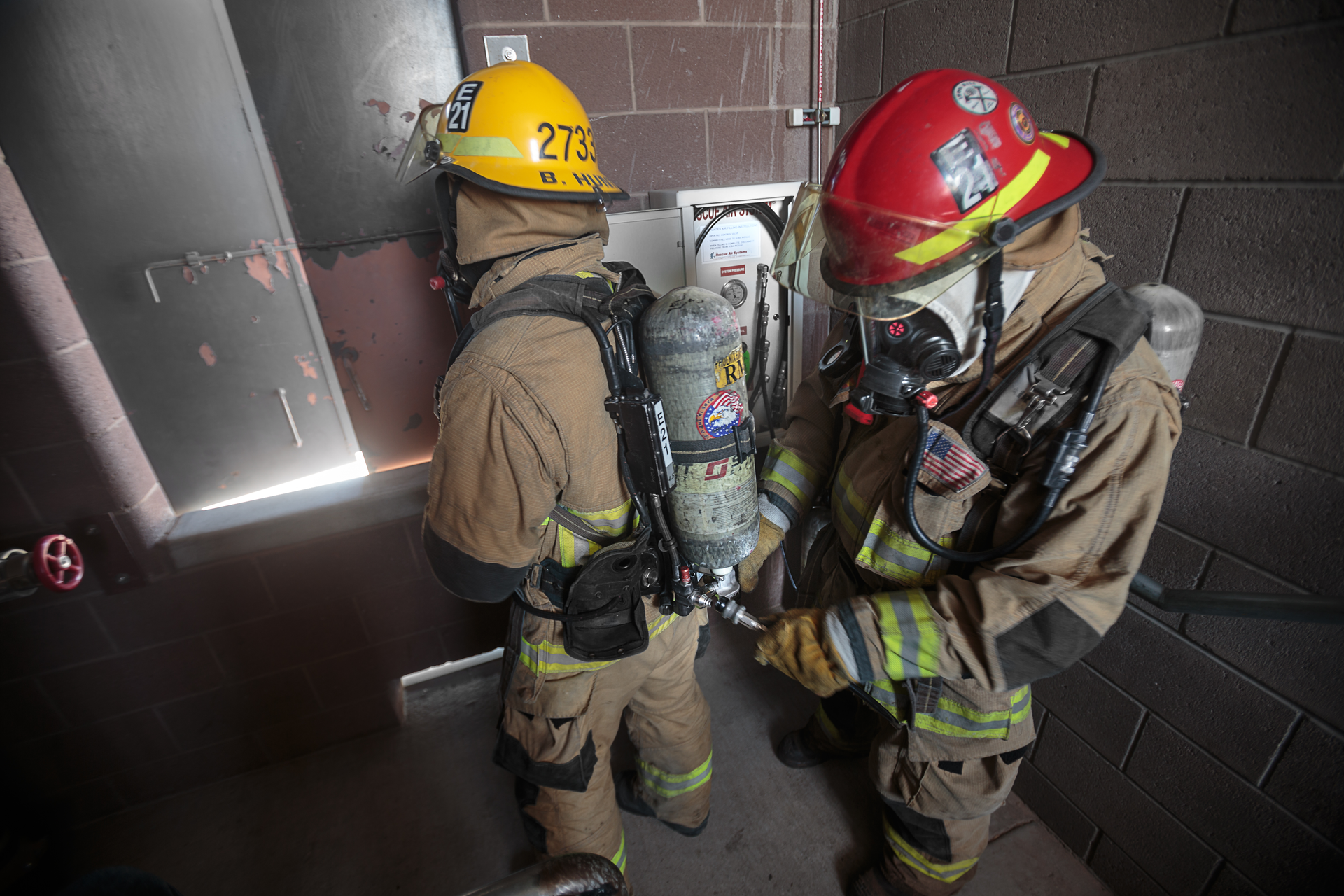 A firefighter refills an air bottle during a high-rise fire using Firefighter Air Replenishment System (FARS) quick fill.