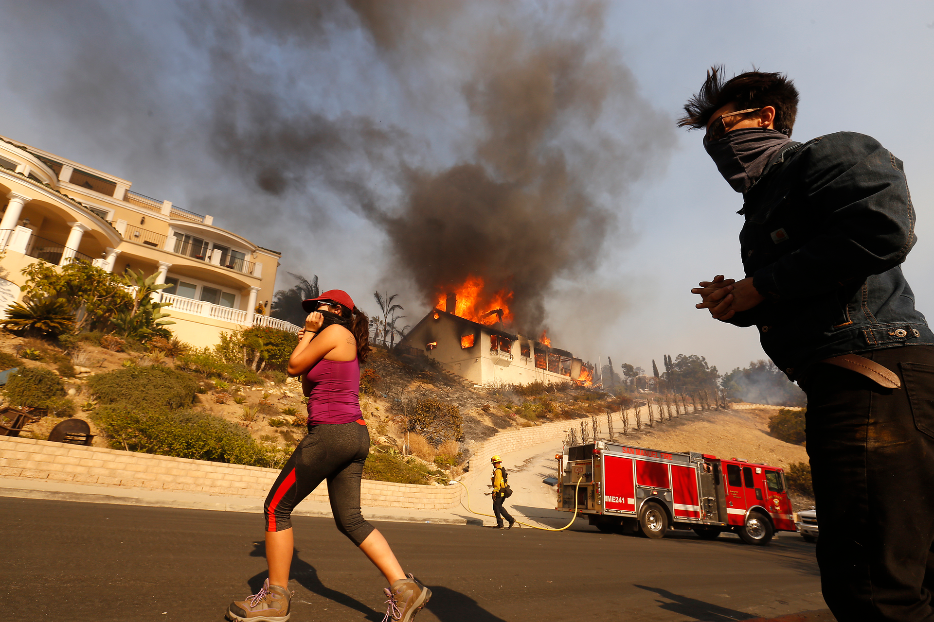 Amanda Leon and husband Johnny Leon watch as firefighters fight to save multi-million dollar homes along Cobblestone Drive Tuesday midday after a fast-moving swept into Ventura destroying many homes.