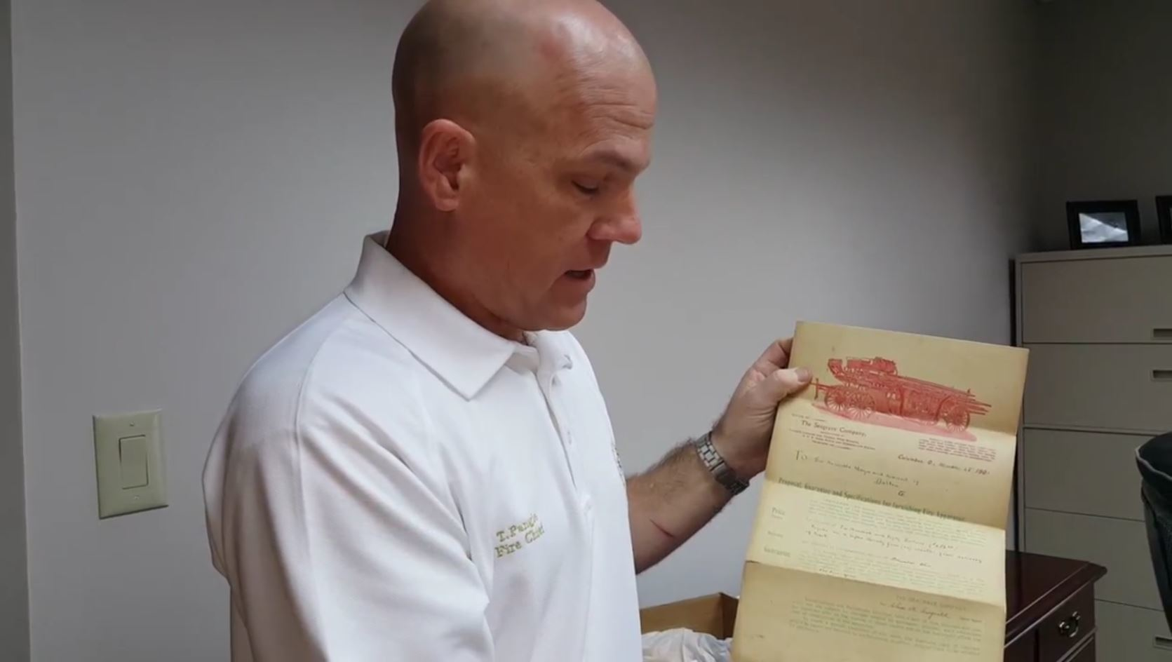 Dalton, GA, Fire Chief Todd Pangle holds up a remarkably well preserved purchase contract for a hook-and-ladder fire truck purchased by the city in 1901.