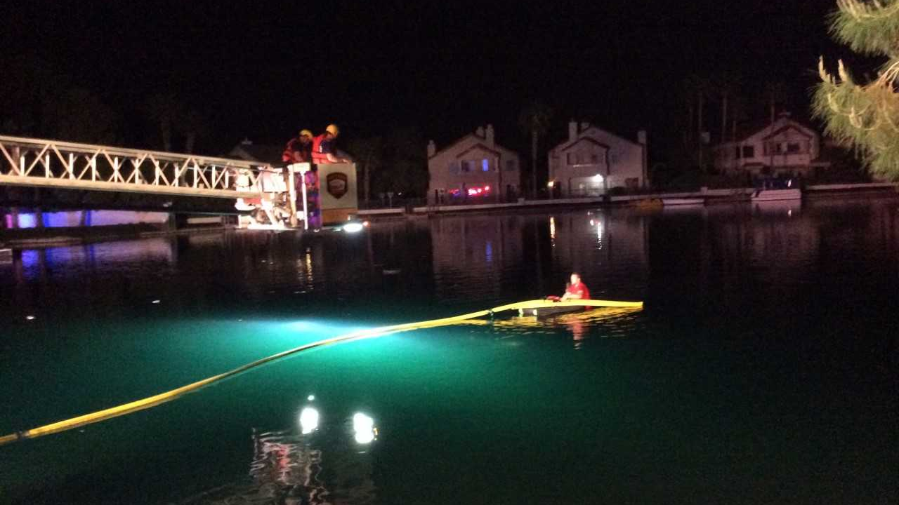 Las Vegas firefighters extend a bucket over a lake in a housing development to pull two people to safety after their car crashed into the water on Tuesday, April 17, 2018.