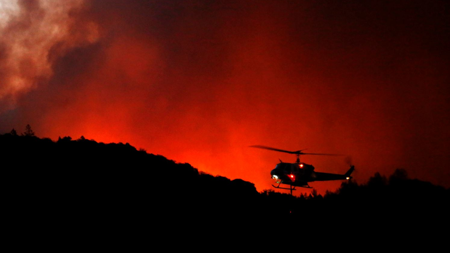 A helicopter prepares to drop water as the Tubbs Fire threatens the Oakmont community along Highway 12 in Santa Rosa, CA, on Oct. 13, 2017.