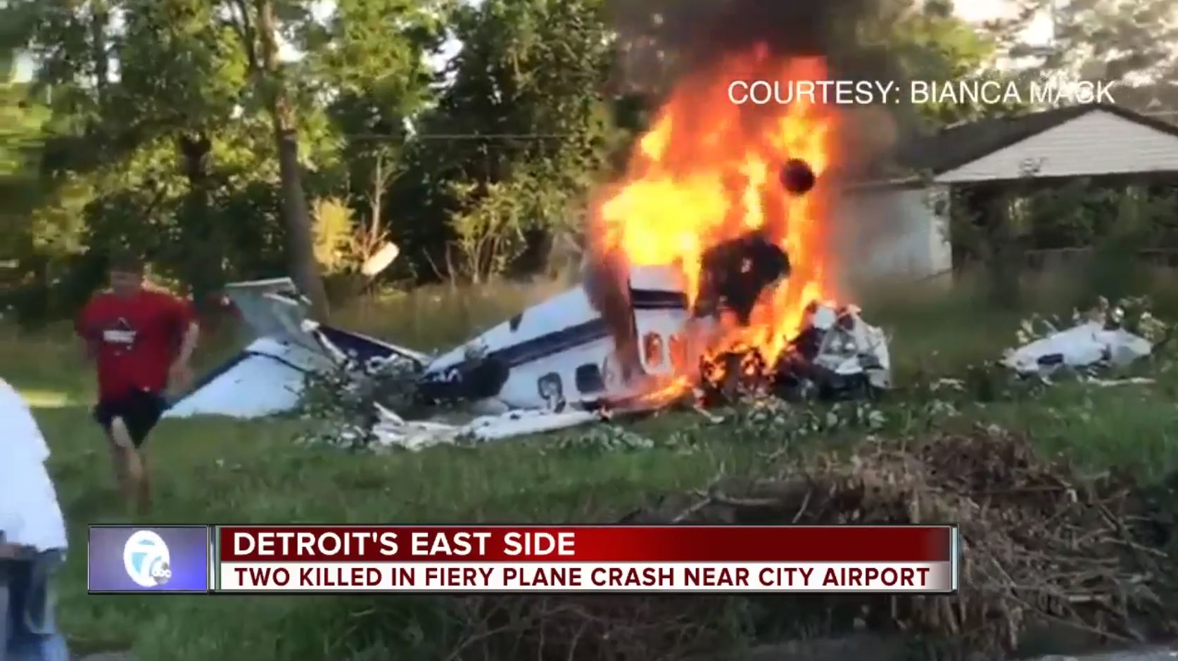 An injured man wearing a red shirt runs away from a plane wreckage in Detroit on Sunday, June 24, 2018, that killed two people.