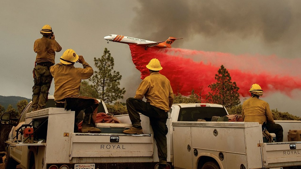 Firefighters watch a plane drop flame retardant on the Ferguson Fire in the Stanislaus National Forest on Sunday, July 22, 2018.