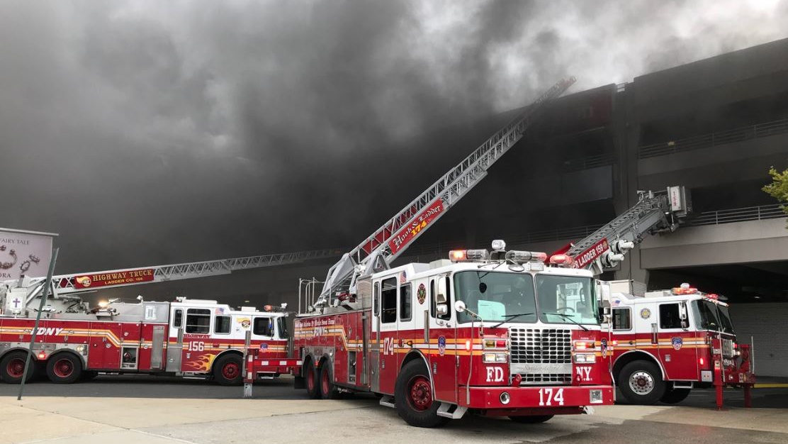 FDNY crews extend ladders along a parking structure at a Brooklyn shopping mall after a disgruntled employee set a fire that consumed dozens of vehicles on Monday, Sept. 17, 2018.