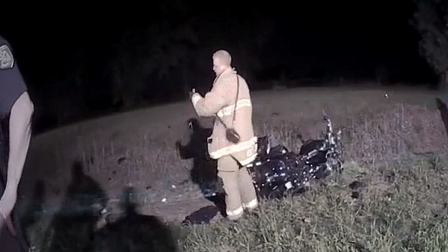 This screen grab from a Macomb County, MI, deputy sheriff's body cam shows firefighter Steven Hart examining a bottle of pills he picked up at the scene of a fatal crash on Aug. 21, 2018.