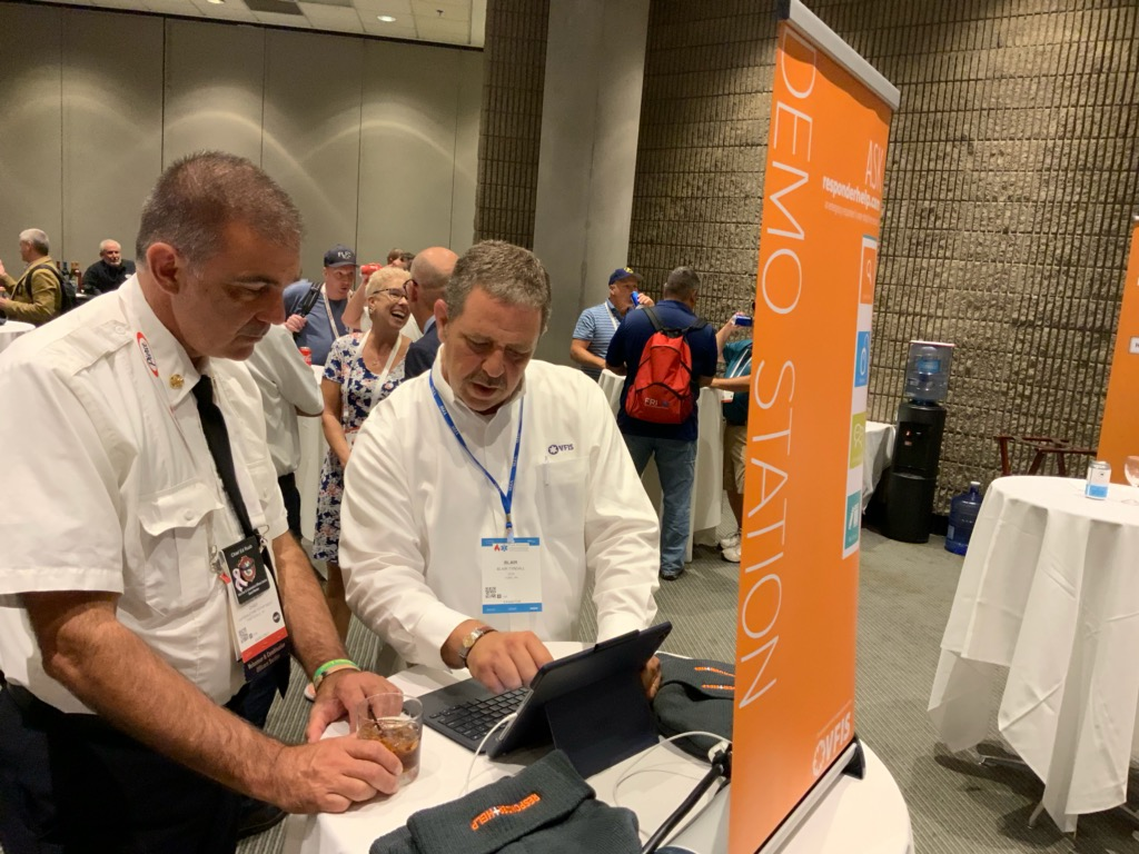Blair Tyndall, right, VFIS Risk Control, demonstrates ResponderHelp.com at FRI.