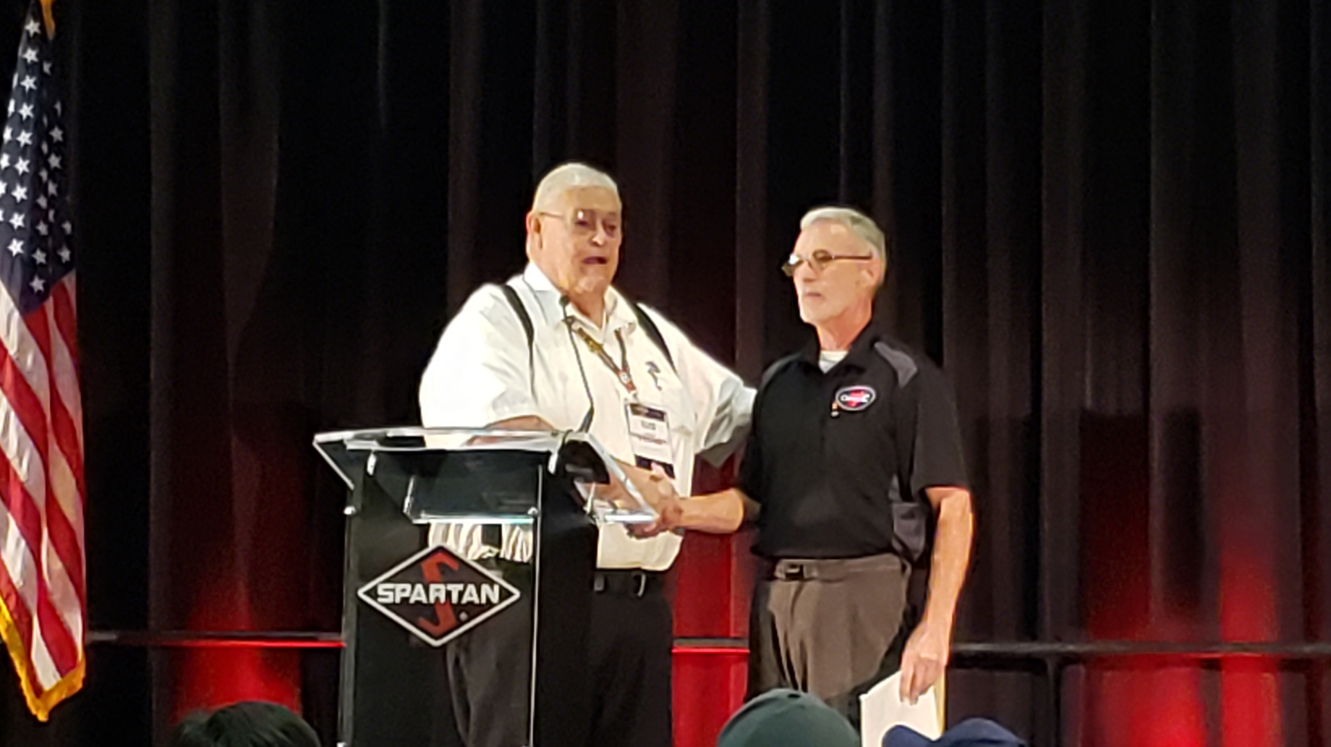 Bill Foster, left, vice president and founder of Spartan Motors, greets 2018 EVT of the Year Al Hasenfratz, right, as he prepares to give remarks at Spartan's Fire Truck Training Conference in Lansing, MI.