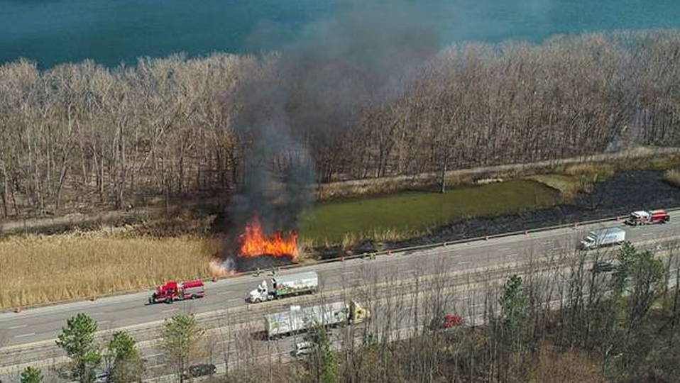 Firefighters from multiple departments trudged through mud and battled 35-foot flames to put out a brush fire along Interstate 690 West near Geddes on Monday.