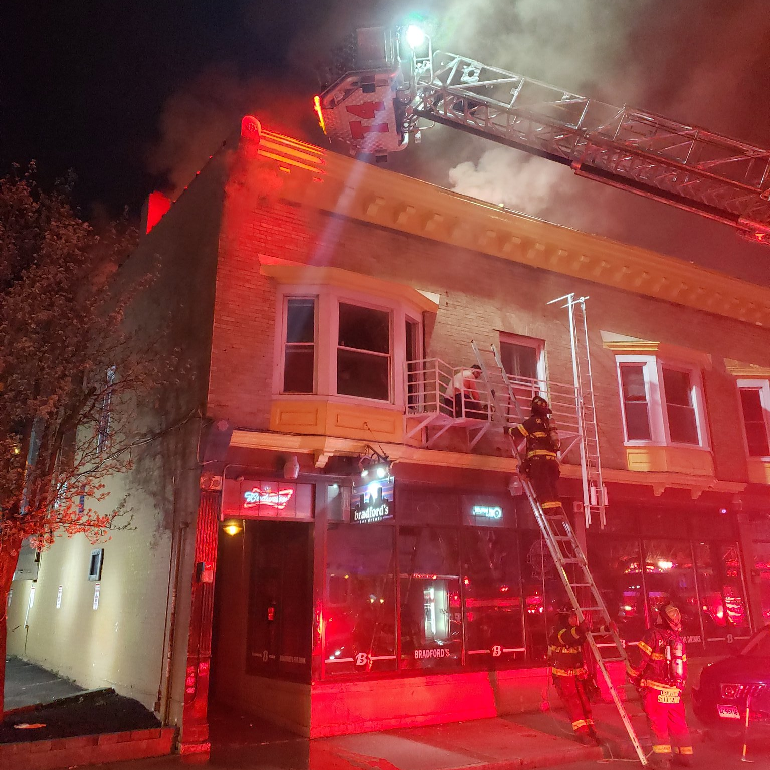 Rochester firefighters use a hand ladder to rescue a resident during a four-alarm fire on Tuesday, April 28, 2020.