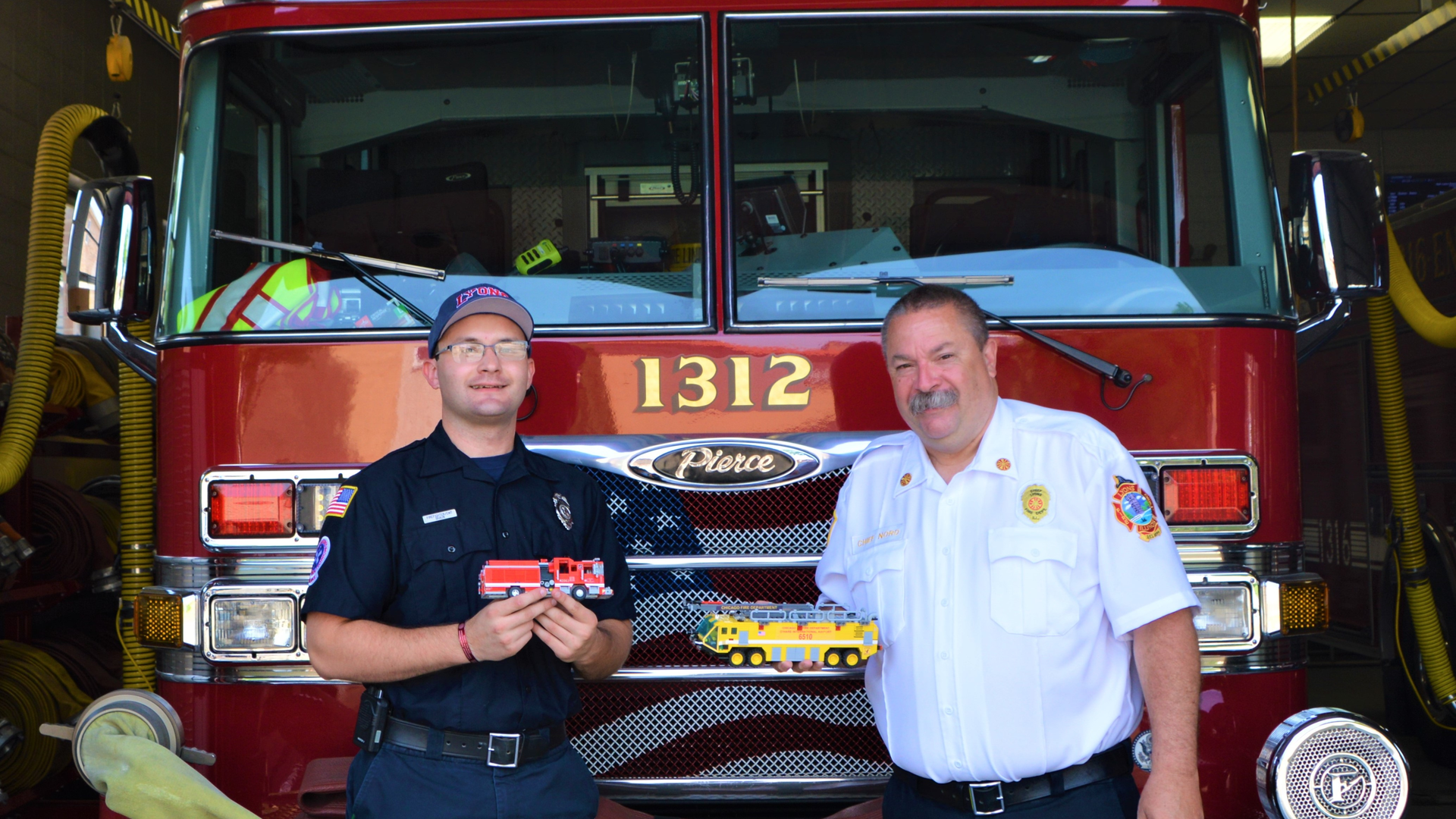 Jeffrey Braun (left), who is a firefighter/EMT-B for the Lyons, IL, Fire Department (LFD), with LFD Fire Chief Gordon Nord, Jr., who is holding one of two airport rescue firefighting vehicles (AARF) that Braun built from Lego blocks. Braun is holding the replica that he built of the Alsip, IL, Fire Department&rsquo;s Engine 2063, which he made for that department&rsquo;s chief.