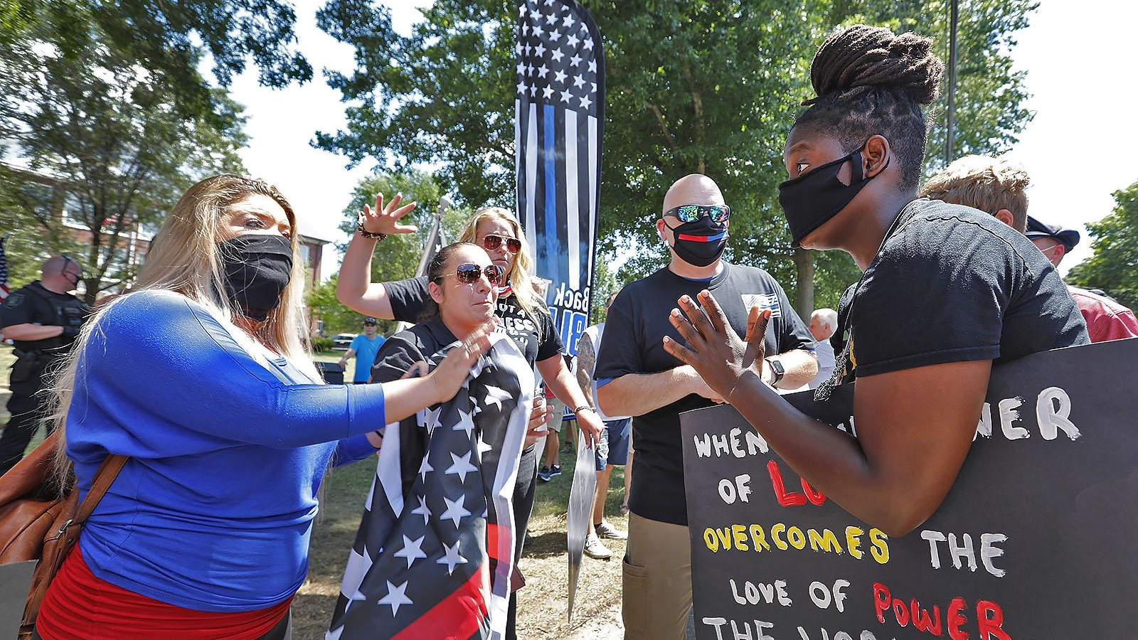 Hingham, MA, resident Anne Pungitore (left) talks Tuesday with Black Lives Matter protester Tru Edwards (right) who came from Boston to counter protest a rally held to object to town officials asking for the removal of 'thin blue line' flags from fire apparatus.
