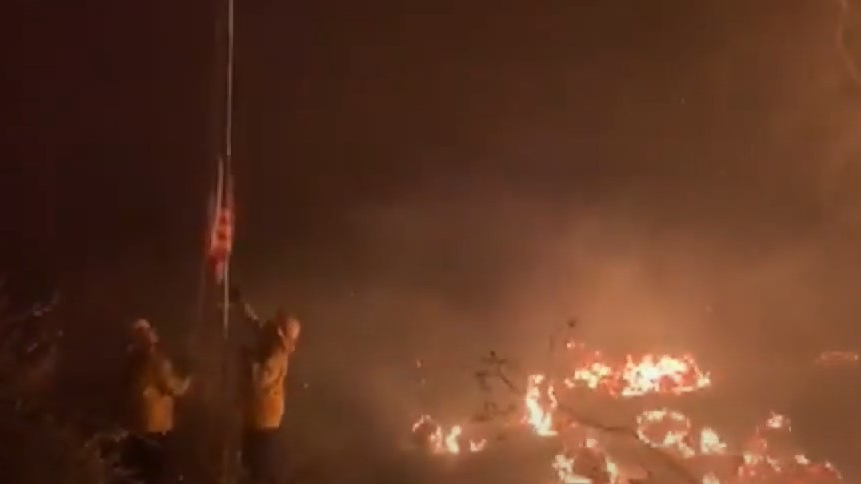 Firefighters save a U.S. flag Wednesday caught in the Lake Fire that has burned more than 10,000 acres in the Lake Hughes, CA.