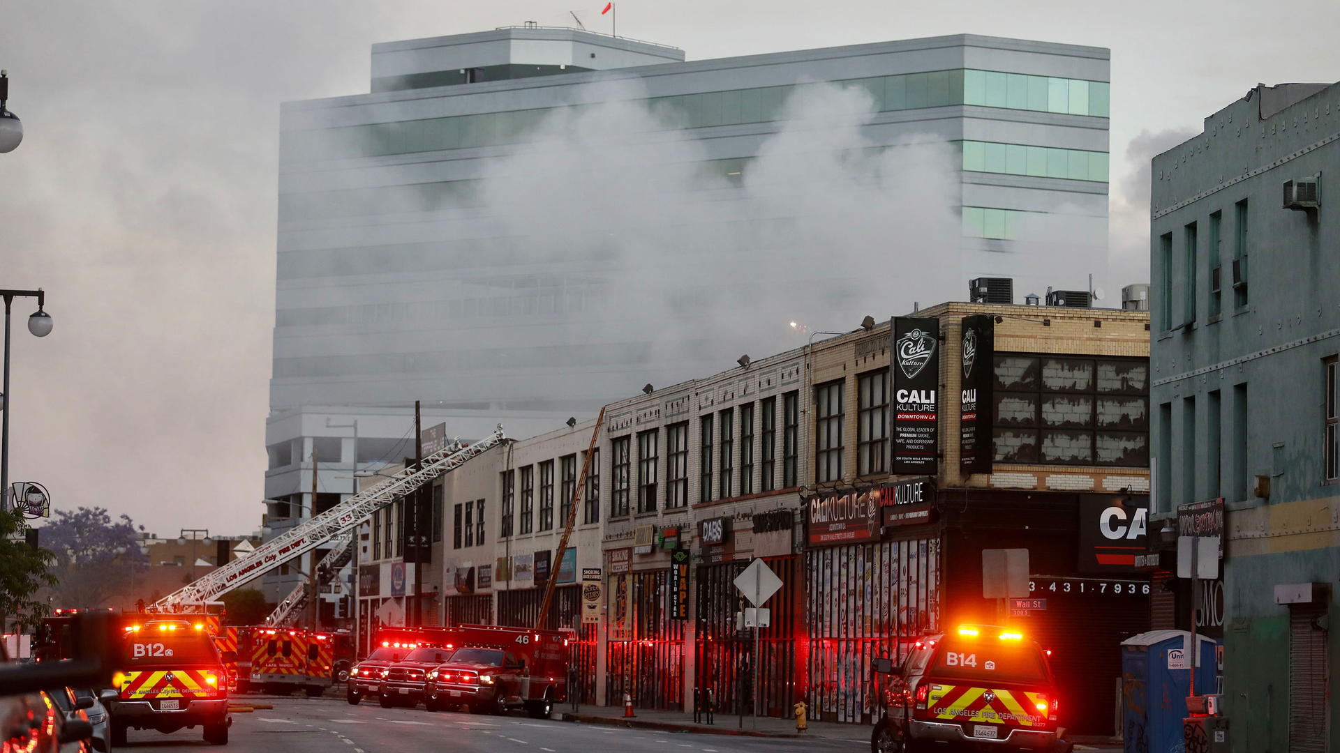 Firefighters at the scene of a commercial fire in downtown Los Angeles that has injured 11 firefighters and left multiple buildings ablaze May 16. The owners connected to the massive downtown explosion face 300 criminal charges.