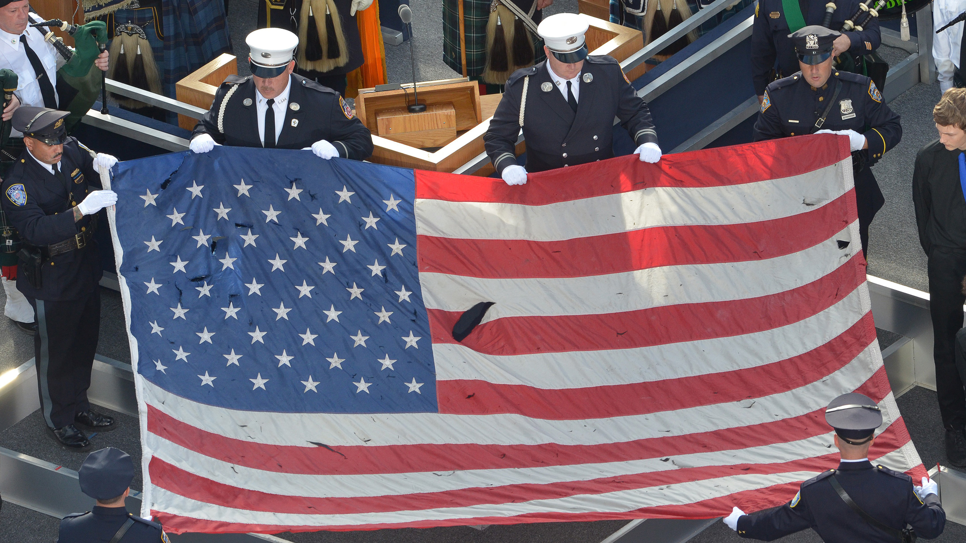 A U.S. flag recovered from the 9/11 attacks is displayed by New York City police officers and firefighters during the ceremony marking the 10th anniversary of the terrorist attack in 2011.