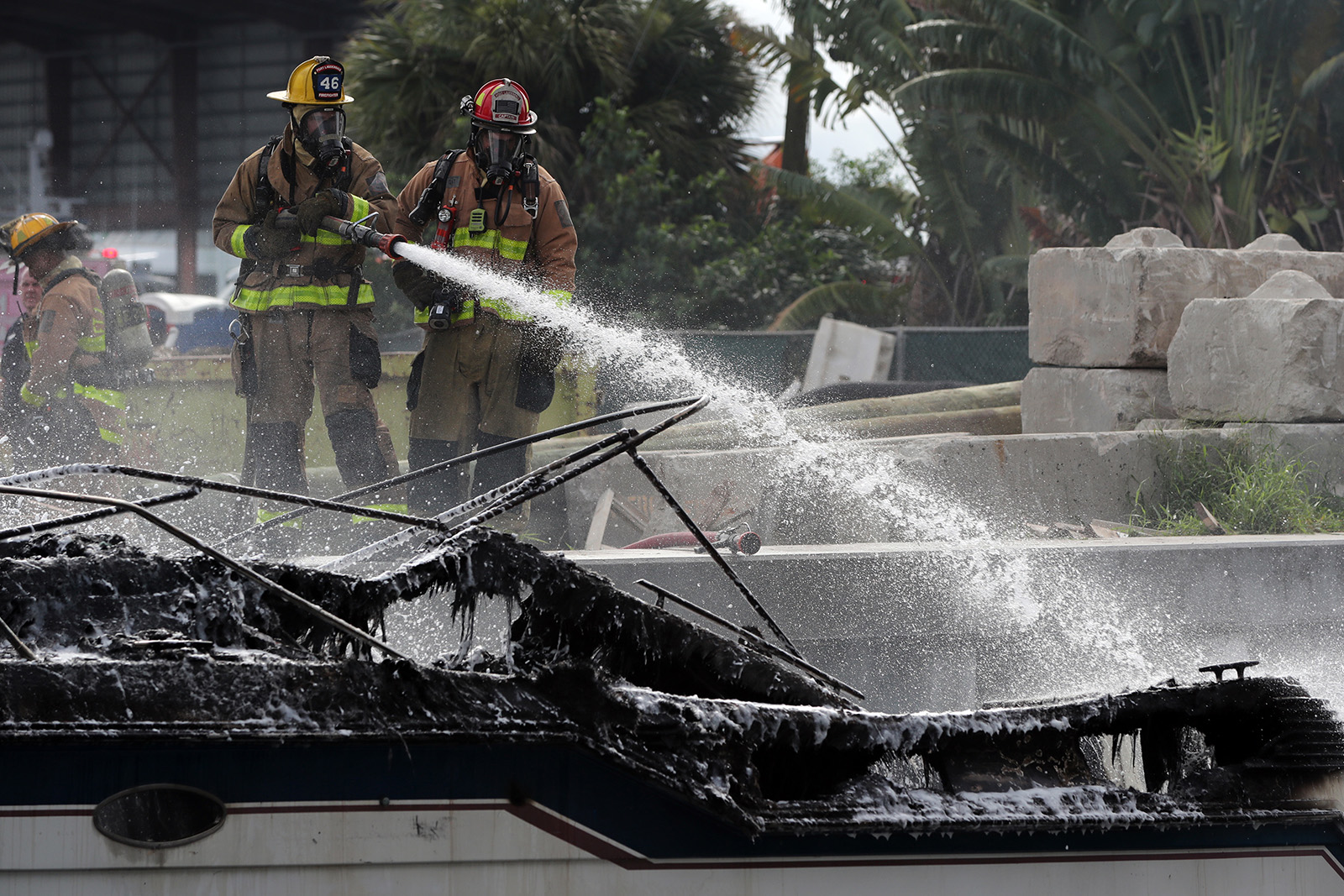 Firefighters work to put out a fire aboard a boat on the New River in Fort Lauderdale, FL, on Thursday that injured at least 13 people.