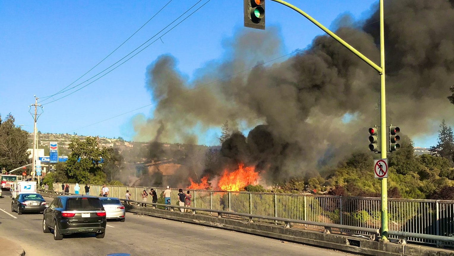More than 50 Oakland, CA, firefighters, as well as crews from other departments, battled a brush fire Thursday that apparently started at a homeless encampment and threatened four structures.