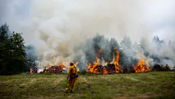 A firefighter stands near a burn line while waiting for a helicopter to dump water during a wildfire training exercise in Molalla, OR. A firefighter stands near a burn line while waiting for a helicopter to dump water during a wildfire training exercise in Molalla, OR.
