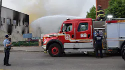 A Minneapolis police officer watches over firefighters who douse the aftermath of a fire following riots in May. A Minneapolis police officer watches over firefighters who douse the aftermath of a fire following riots in May.