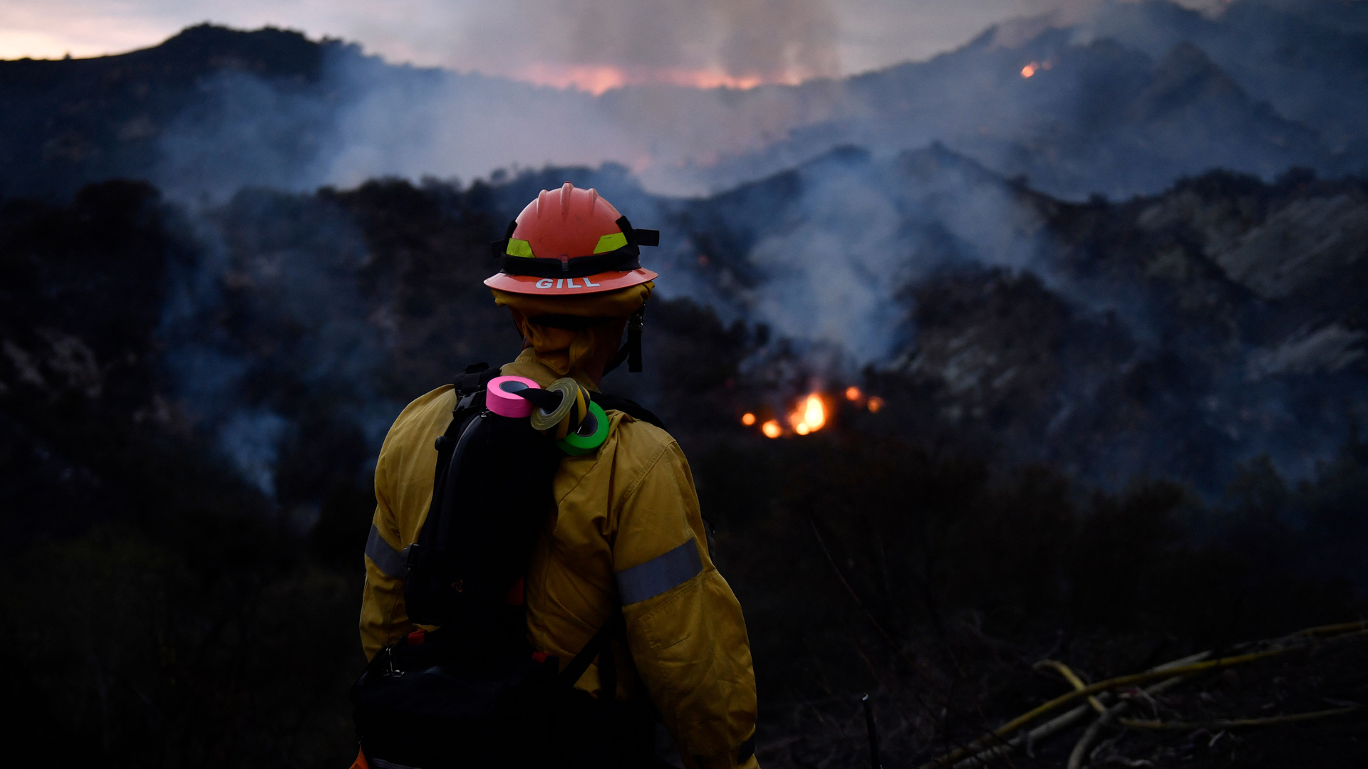 A firefighter watches the flames from the Palisades fire glow in the distance in Topanga State Park, North West of Los Angeles on May 15, 2021. - A brush fire near Pacific Palisades started Friday and grew to 750 acres Saturday nt, triggering a mandatory evacuation of residents in the Topanga area. (