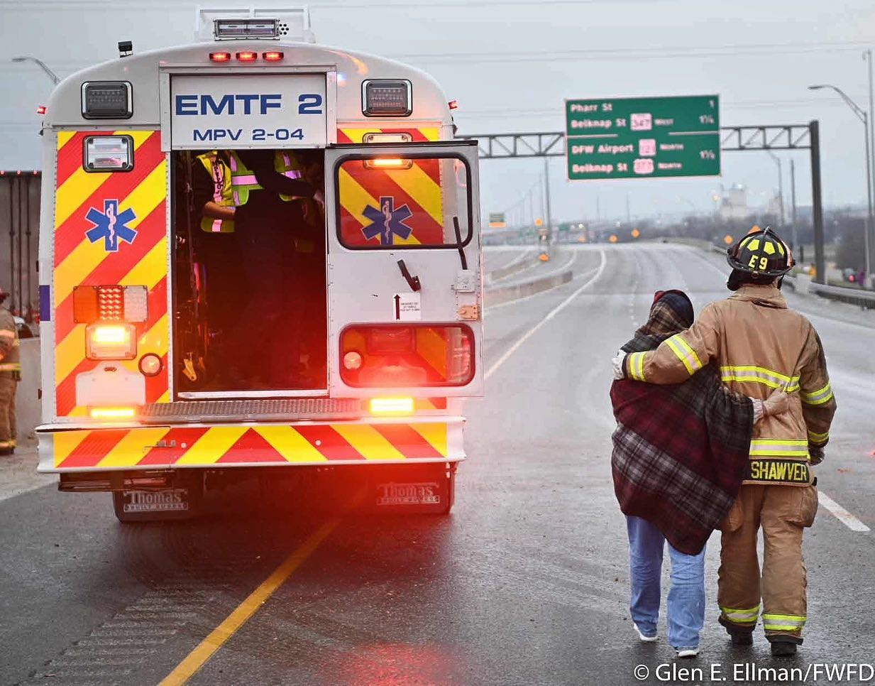Fort Worth firefighter Case Shawver accompanies a woman to a medical bus after she was removed from 133-car pileup on Interstate 35W.