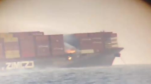 Flames can be seen among shipping containers on a cargo vessel sitting about 5 miles off the coast of British Columbia on Saturday, Oct. 24, 2021.
