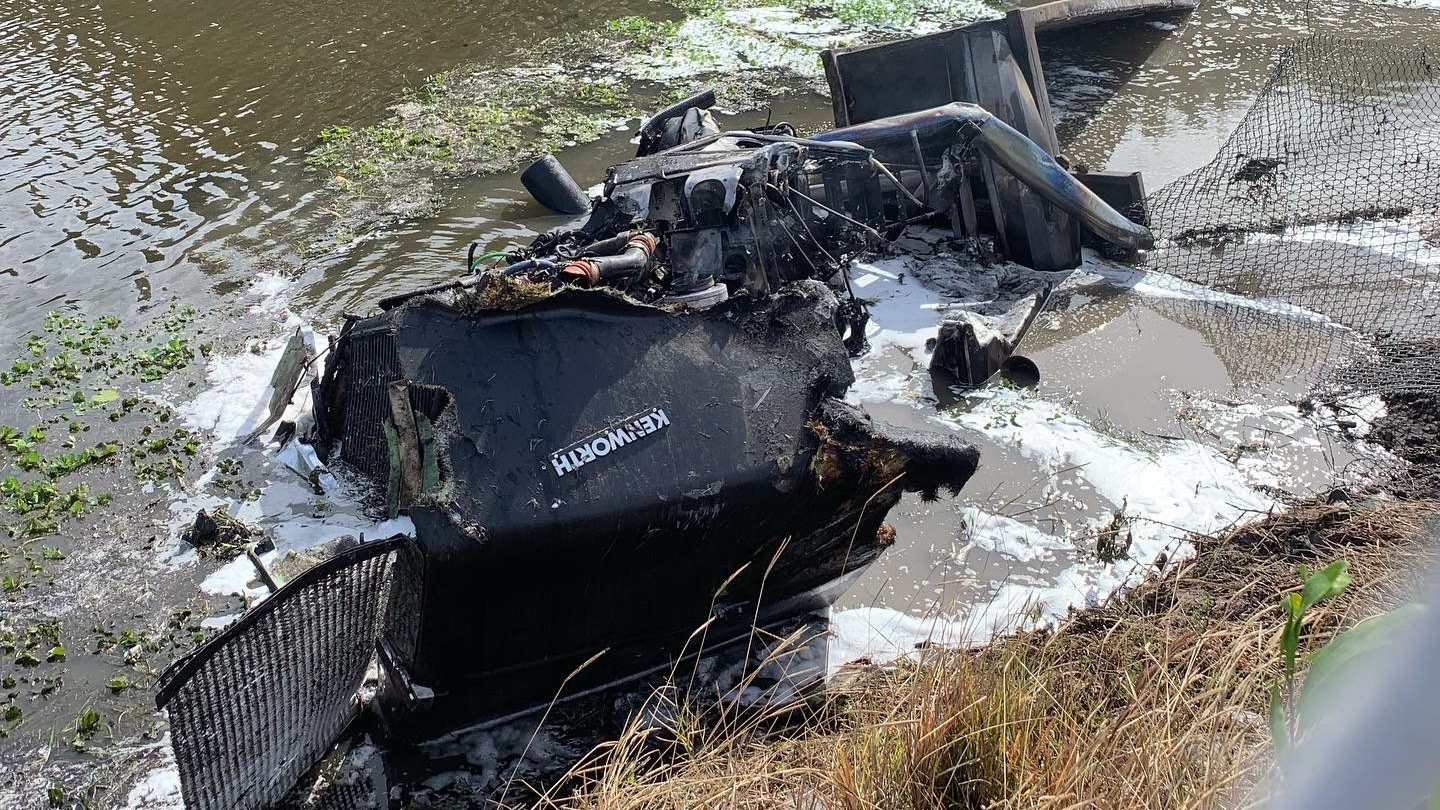 The shell of a burned-out semi-truck sits in a canal in Boynton Beach, FL, after crashing and catching fire on Wednesday, Nov. 17, 2021.