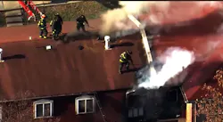 Saint Louis firefighters open up the roof during an apartment fire. Saint Louis firefighters open up the roof during an apartment fire.