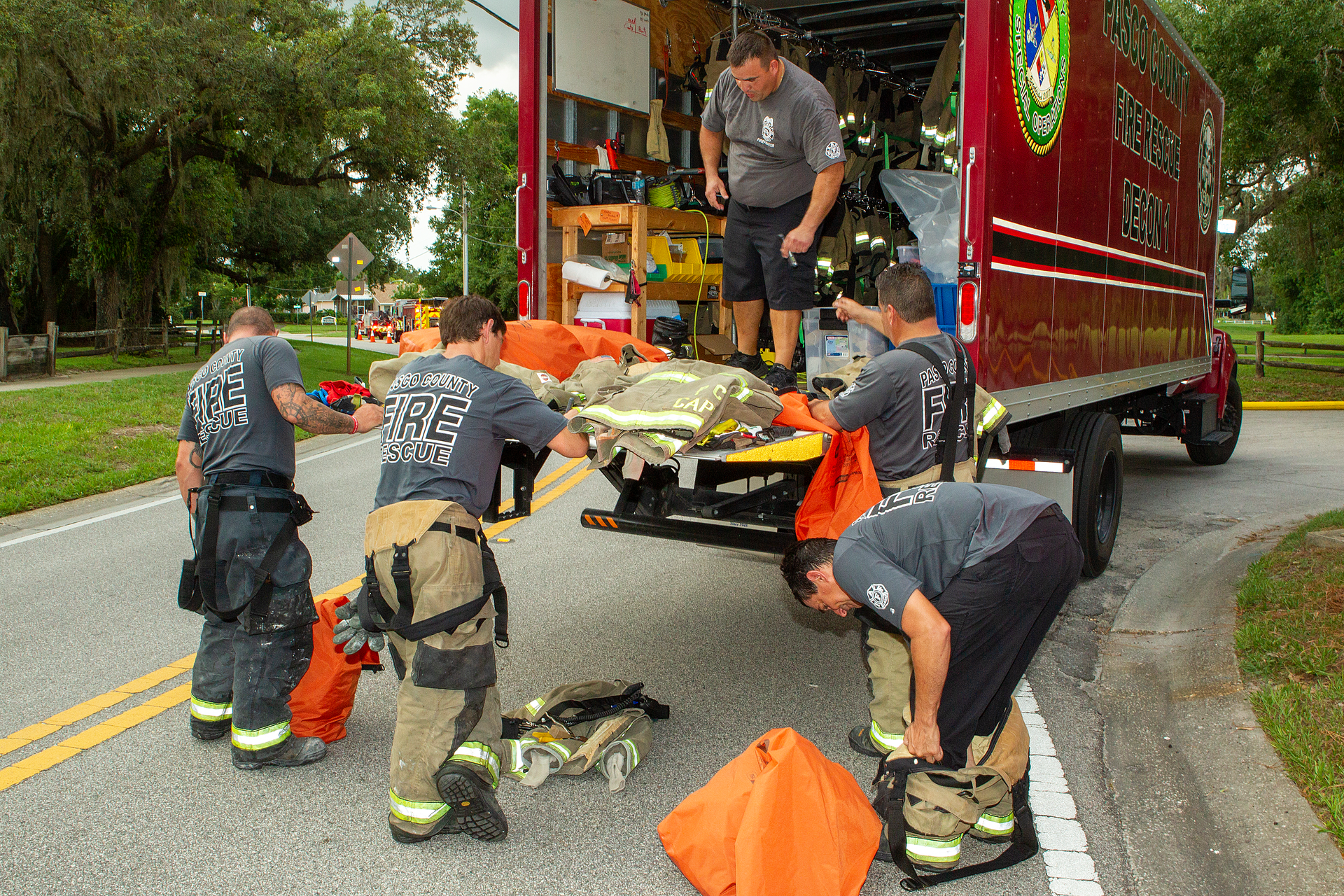 Pasco County, FL, Fire Rescue (PCFR) members swap turnout gear that they wore for a structure fire for a clean set of gear that a decon technician brought to the scene.