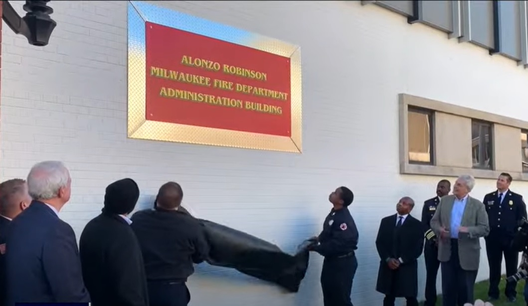 Milwaukee firefighters unveil a plaque honoring architect Alanzo Robinson.