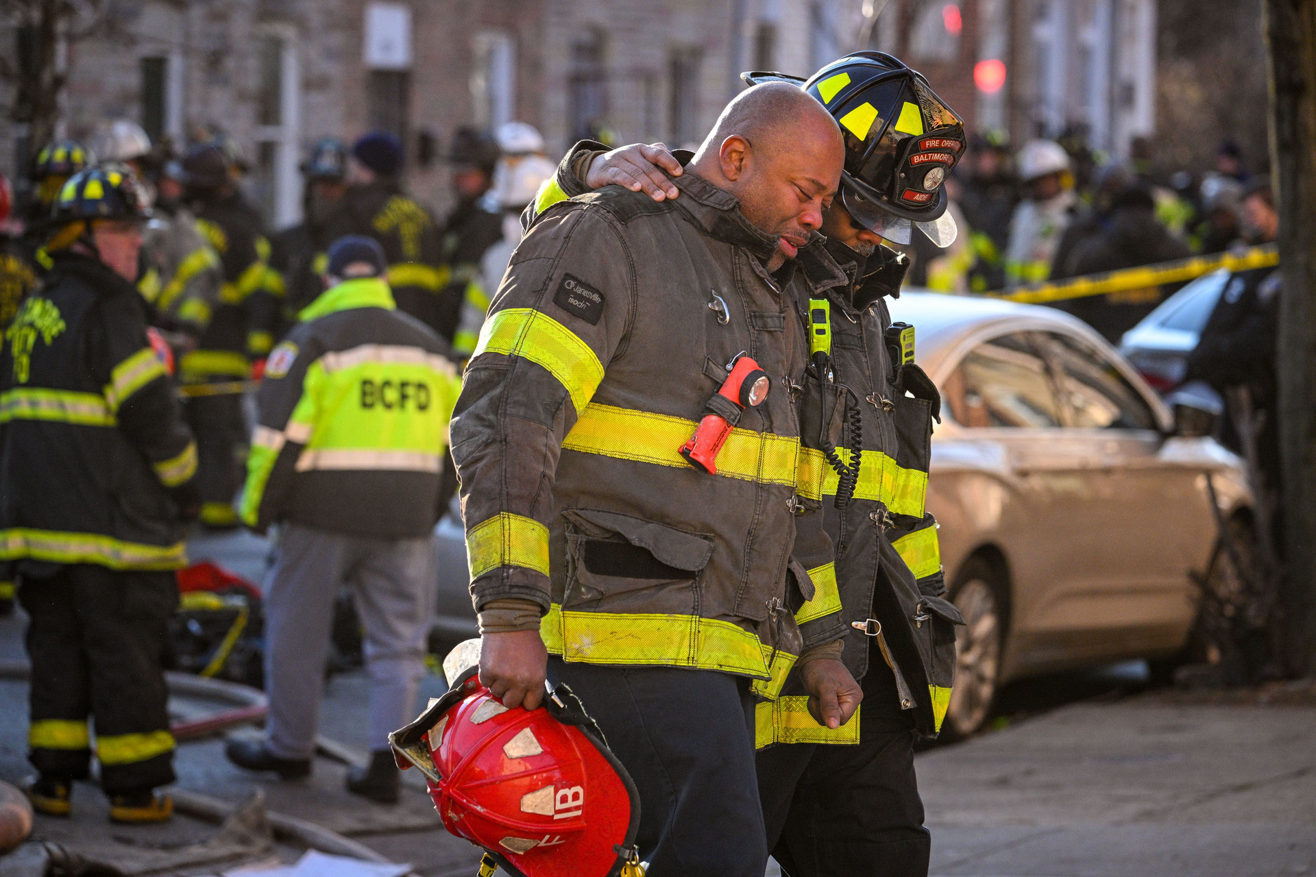 Members of the Baltimore City Fire Department walk away from the scene of a vacant rowhouse fire on S. Stricker Street where four firefighters had been trapped.