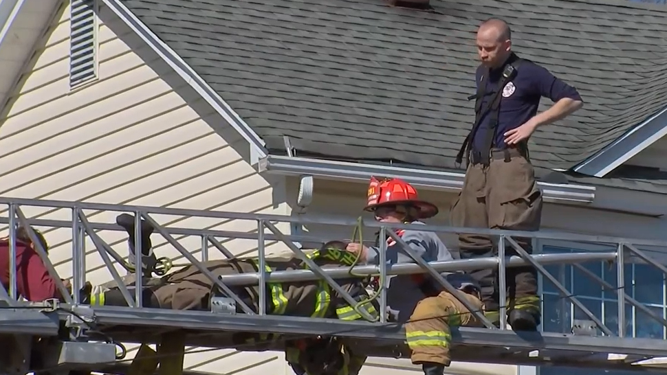 Firefighters work to free Richard Schuller after his feet got caught in an aerial ladder during a duplex fire Monday.
