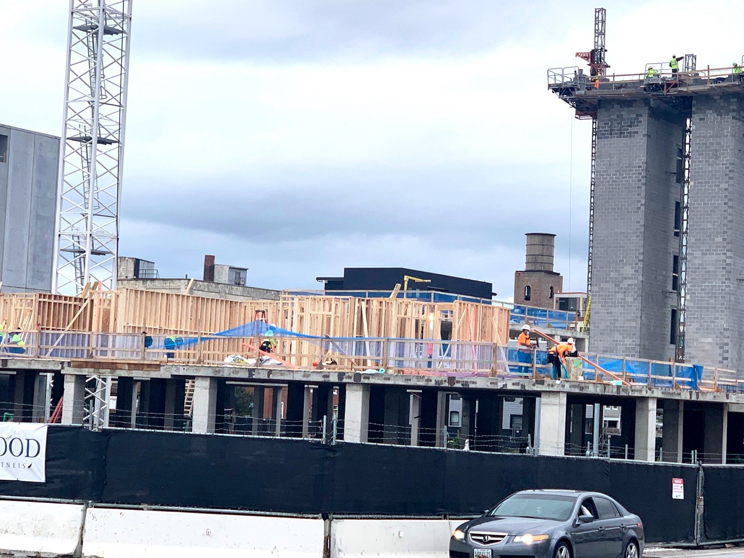 The unique facets of the construction of a building that has a 'podium' on bottom and a wood-frame structure on top include the fact that building systems traverse through a horizontal separation.