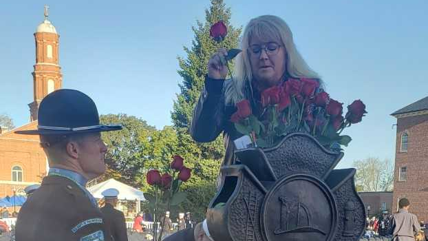 Traci Adams Swartz places roses at the entrance of National Fallen Firefighter Memorial early Sunday morning.