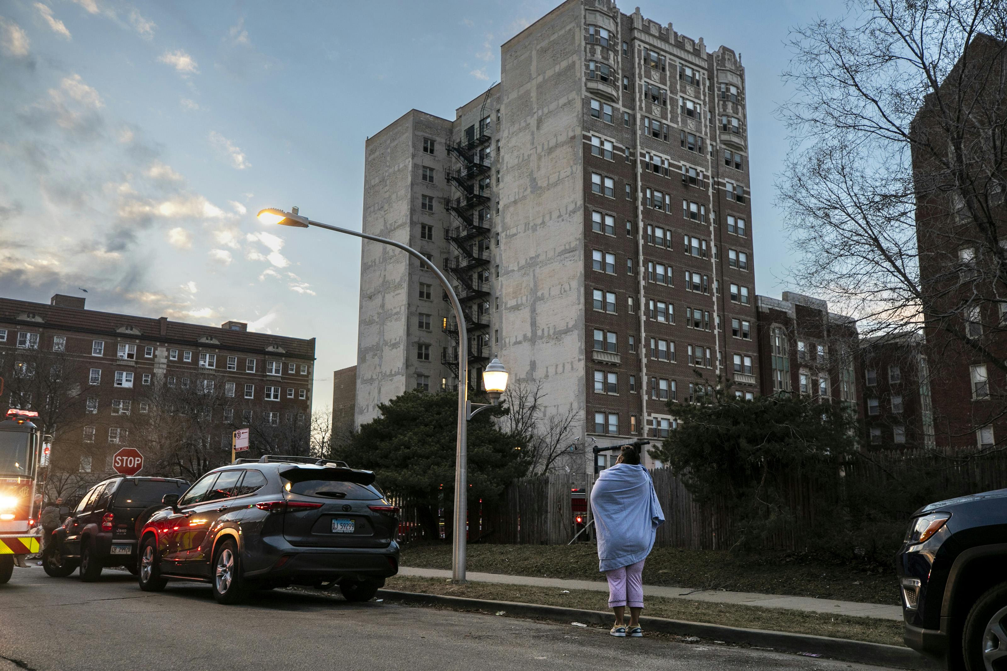 A resident watches as firefighters work at a high-rise fire in the 7100 block of South Jeffery Boulevard.