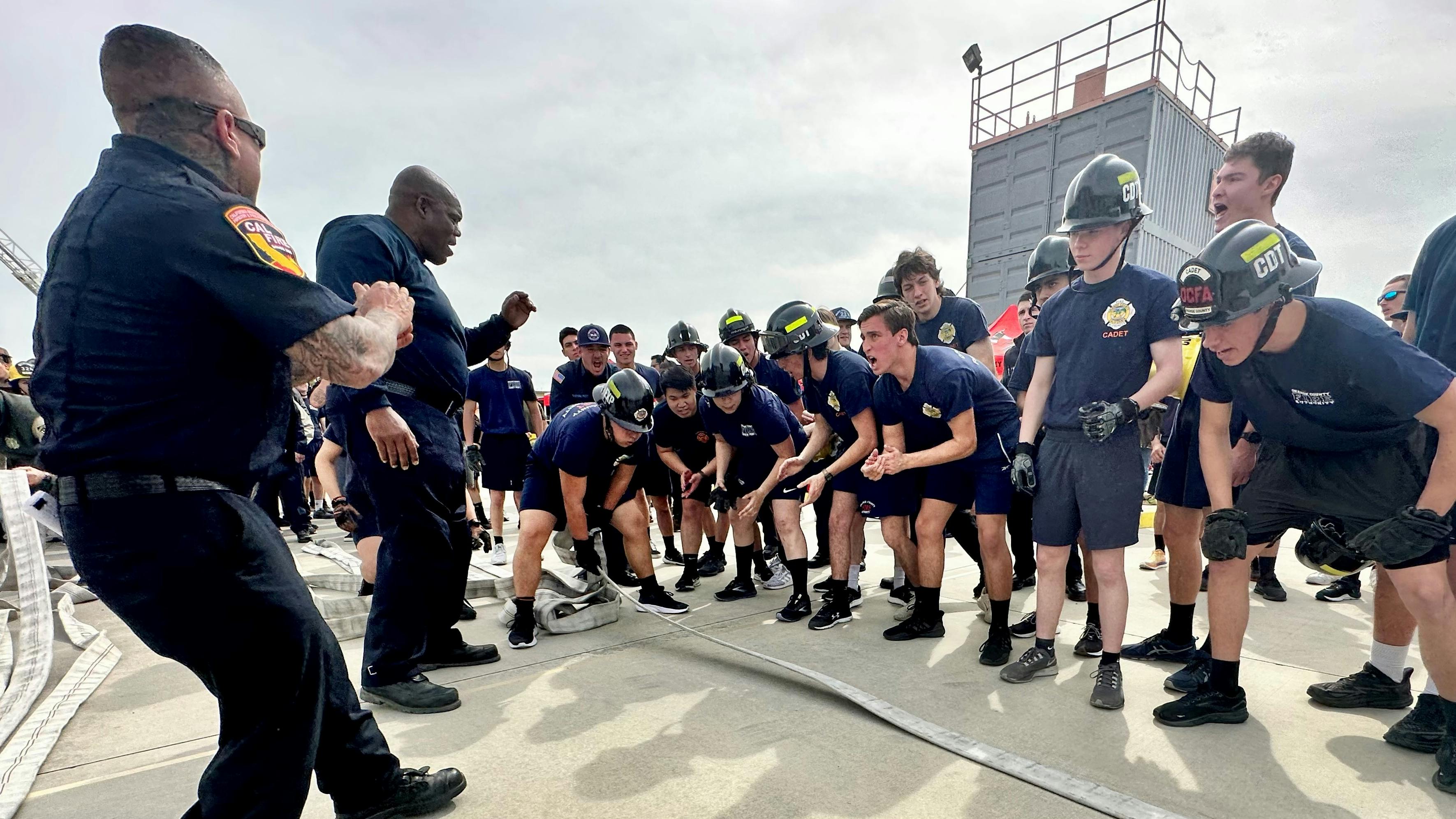 Explorers and advisors cheer as an explorer pulls hose across a line during the monster.